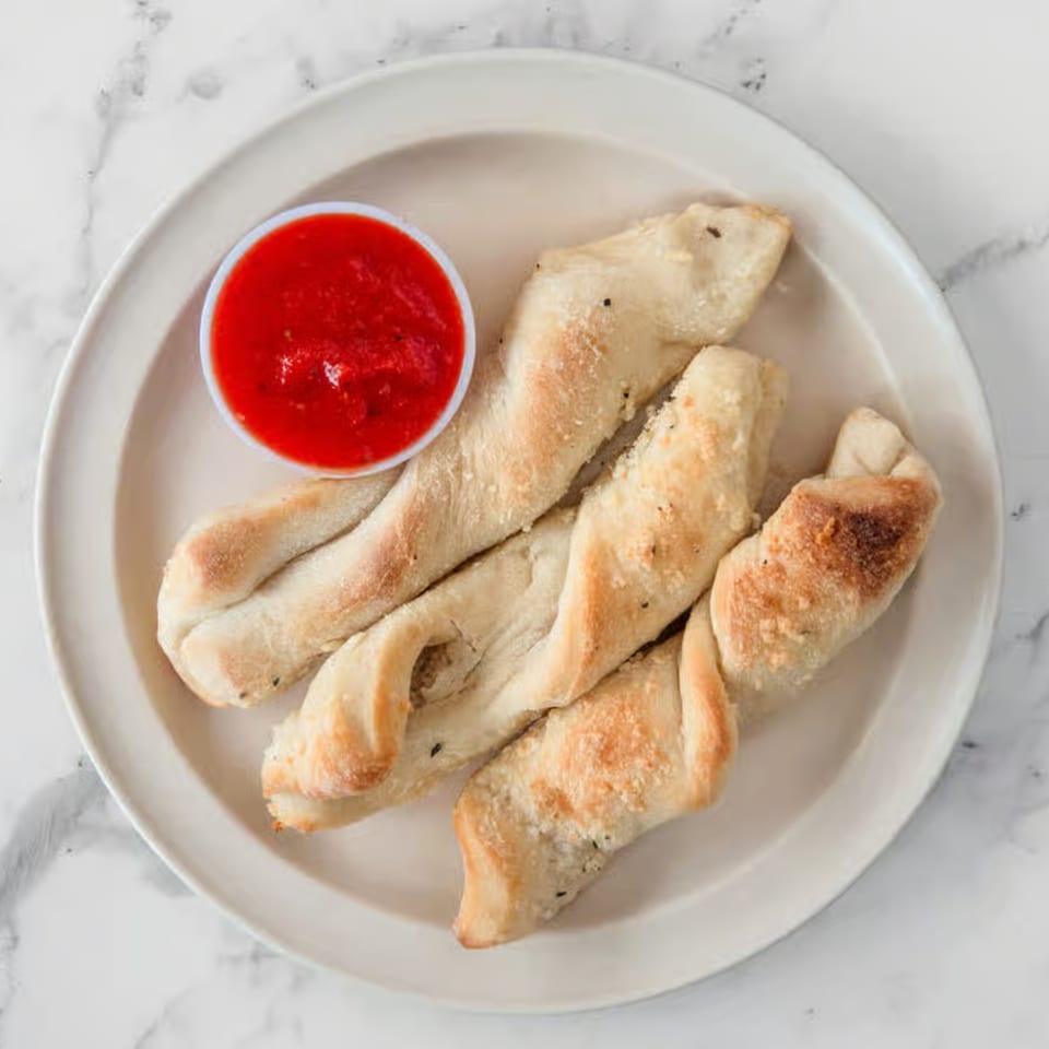 Four twisted breadsticks with parmesan cheese and herbs, served with a side of marinara sauce.