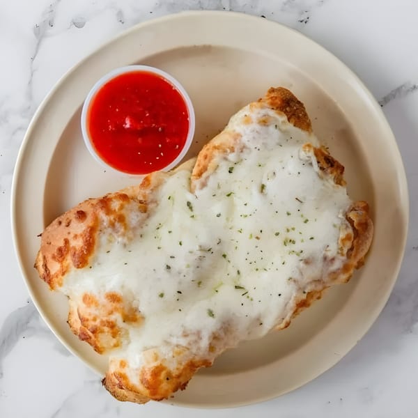 Iriana's Pizza's cheesy bread with herbs, served with a side of red marinara sauce.